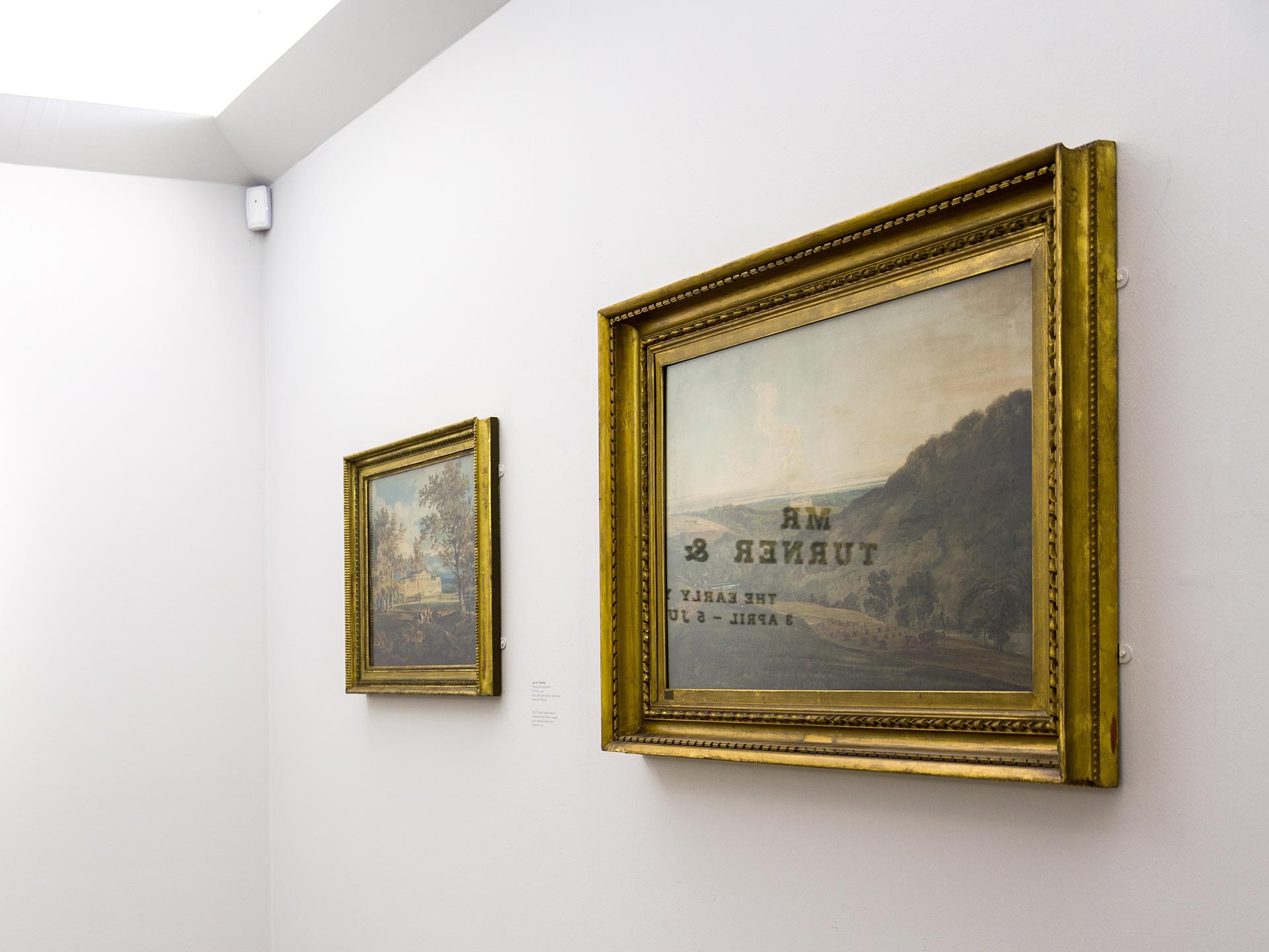 Title wall reflected in the glass of a framed painting