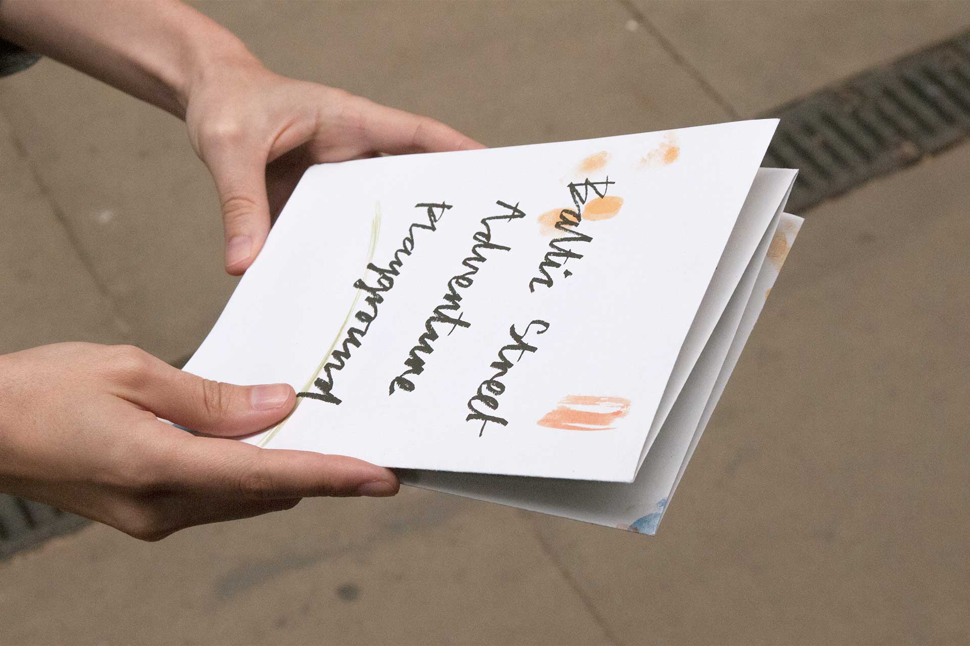 Booklet held in a pair of hands, demonstrating the folding style