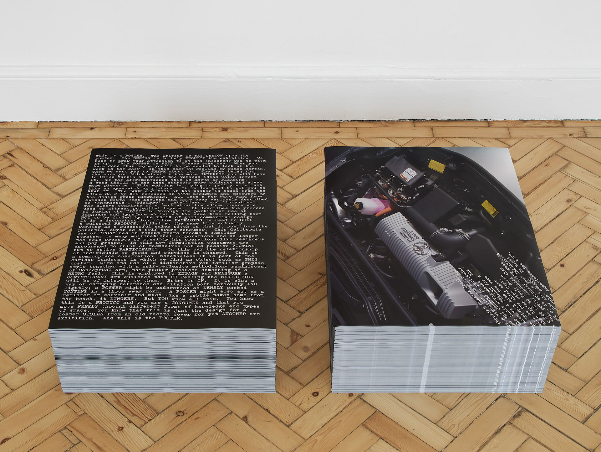 Stacks of posters on a parquet floor in the gallery